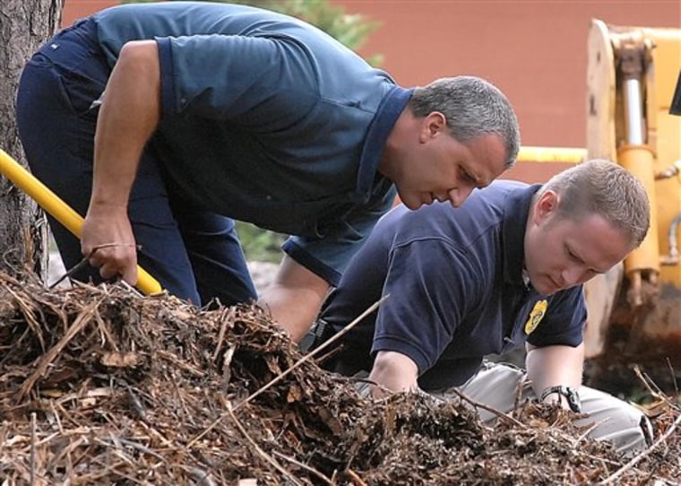 Doug Dupell, left, street maintenance supervisor for the City of Hickory and Hickory Police Investigator Rob Burwell sift through mulch at the home Zahra Baker for the second day in a row, Thursday, Oct. 28, 2010  in Hickory, N.C.. Law enforcement agencies are going through the residence and backyard for more evidence. (AP Photo/The Hickory Daily Record, Robert C. Reed)